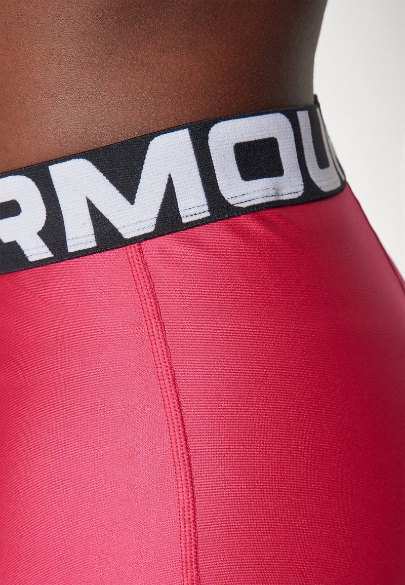 Rosa sportliche Shorts verfügen über einen schwarzen elastischen Bund mit weißem Text. Der Stoff hat eine glatte Textur und sichtbare Nahtdetails.