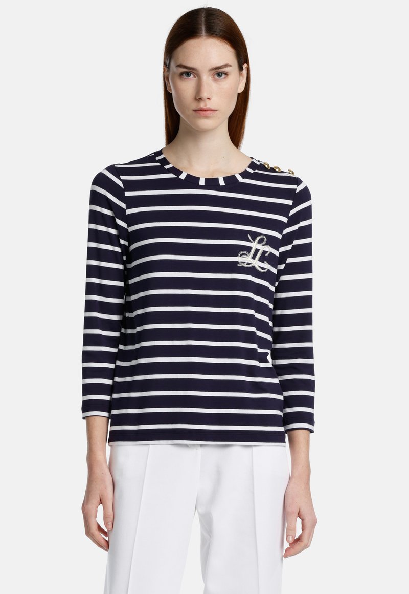 Navy-en witte gestreepte blouse met lange mouwen en een ronde hals, met een logo-detail en knoopaccenten op één schouder.