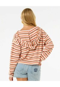 Felpa a righe in crema, ruggine e viola chiaro, con una vestibilità comoda, cappuccio con coulisse e texture a coste. Abbinata a pantaloni corti in denim.