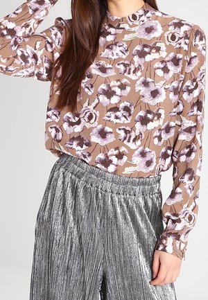Blusa a maniche lunghe marrone con stampa floreale viola; abbinata a pantaloni larghi plissettati argento; tessuto morbido e vestibilità rilassata.
