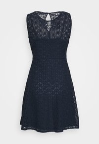 Mörkblå spetsklänning med ärmlös design, vågformad halsringning och en nyckelhålskärning på baksidan. A-linjeformad siluett och strukturerat mönster.