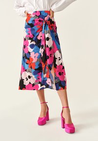 Falda midi floral con patrones vibrantes en rosa, azul y negro; confeccionada en tejido ligero; presenta una cintura anudada y una abertura lateral.