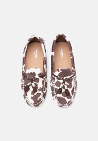 Pair of Valentino brown and white cow-print moccasins with tassels on a white background.
