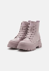 Botine cu șireturi, realizate dintr-un material lucios de culoare mov deschis, având o talpă masivă cu striații adânci și o etichetă cu logo pe toc.