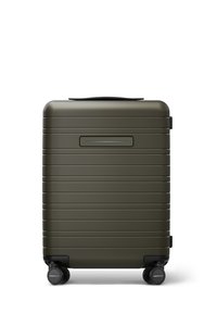 Valise rigide de couleur olive avec une surface texturée et rainurée, une poignée supérieure et quatre roues noires pour la mobilité.