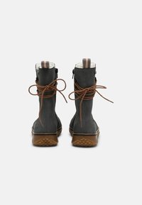 Hallide saapad, millel on tekstureeritud kangast pealisosa, pruunad põimikud ja kummist tallad.  Ülemises osas ja külje tõmblukul on triibuline kangast aksent.