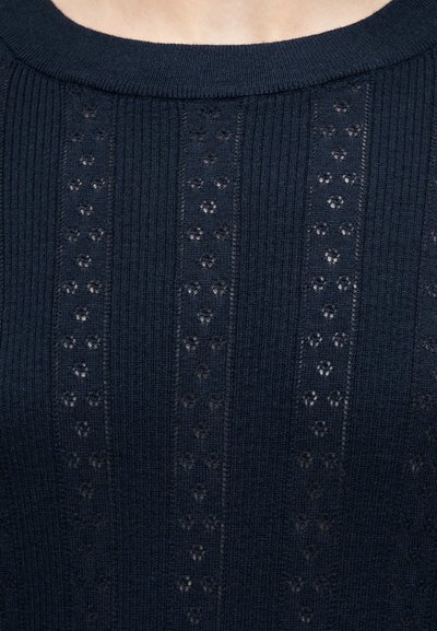 Πλεκτό τοπ ναυτικού μπλε με κάθετες σειρές από μικρά λουλουδάτα ανοίγματα και στρογγυλή λαιμόκοψη.