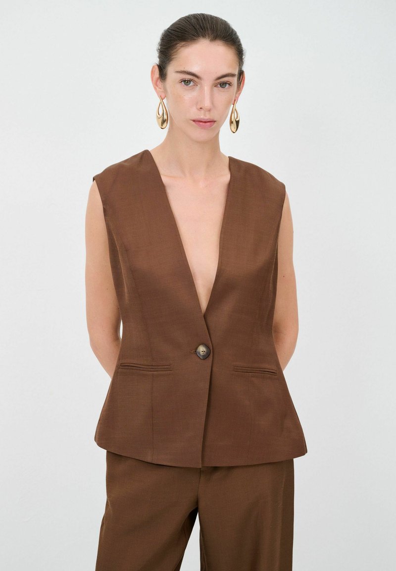 Brauner ärmelloser Blazer mit tiefem V-Ausschnitt, einem Knopfverschluss und zwei Vorderaschen. Glatte Textur, taillierte Form.