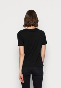 Camiseta de algodón negra con mangas cortas, escote redondo y un corte relajado. La tela parece suave con un ligero estiramiento.