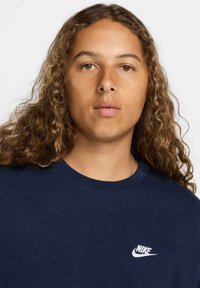 T-shirt in cotone colore blu navy con collo a giro e maniche corte, caratterizzato da un logo Nike ricamato in bianco sul lato sinistro del petto.