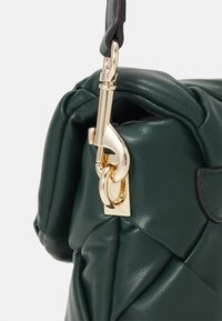 Sac à main en cuir vert avec une texture matelassée, quincaillerie dorée et une seule bandoulière avec attache à clip.