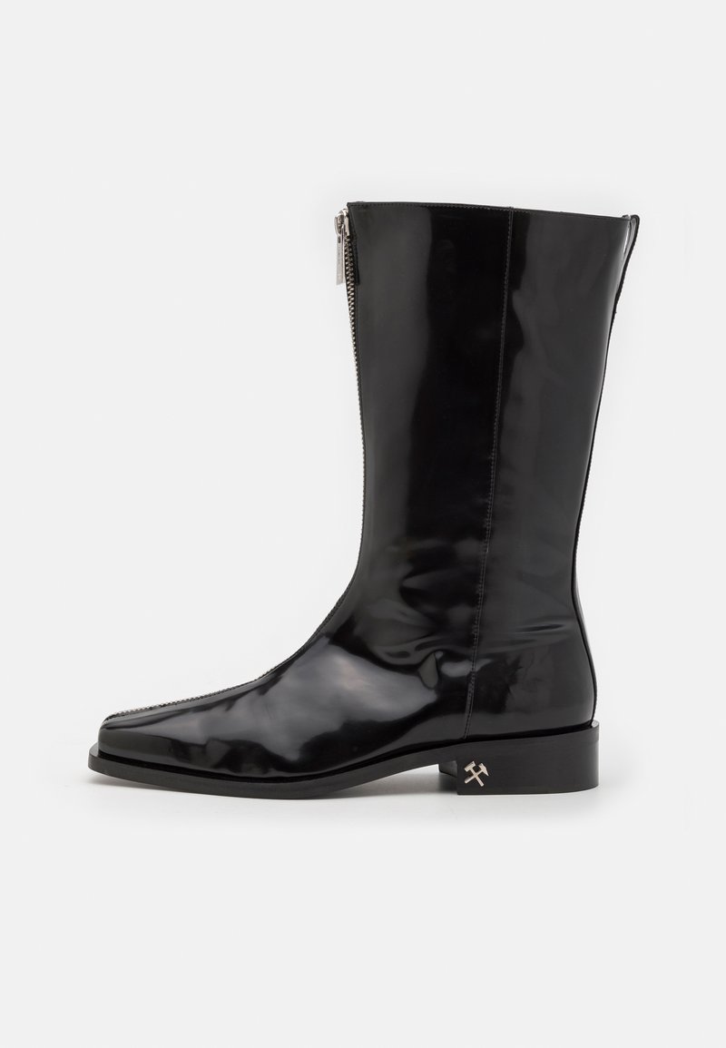 Cizmă neagră, cu un luciu intens, până la genunchi, cu vârf rotund, fermoar lateral și un toc mic pătrat, având un accent cu logo-ul de argint în formă de ciocan.