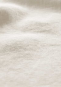 Lichtbeige linnenstof met een zachte textuur, subtiele kreuken en een natuurlijk geweven patroon, wat een lichtgewicht en ademende kwaliteit uitstraalt.