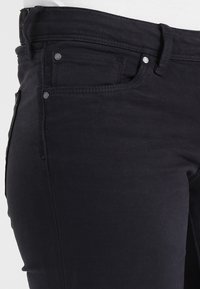 Black denim jeans featuring a slim fit, five-pocket design, contrast stitching, and metal hardware accents. Smooth texture with slight stretch.