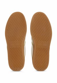 Sole delle sneaker con una finitura in gomma testurizzata, caratterizzata da un motivo a battistrada triangolare. Logo "TOMMY JEANS" impresso su una delle suole.