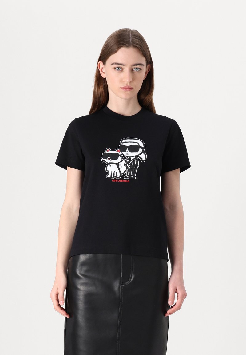Svart bomull t-shirt med en framsida som har en grafik av två karaktärer i solglasögon. Korta ärmar och rund nacke. Slät textur.