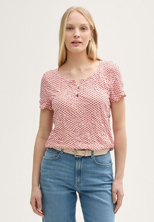 Top a maniche corte rosso e bianco con un collo rotondo e dettagli con bottoni, abbinato a jeans in denim azzurro chiaro e una cintura beige.