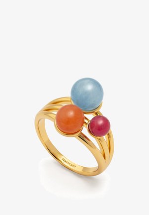 Guldtonet ring med tre runde ædelsten: en lys blå, orange og pink, anbragt på buede bånd for et lagdelt design.