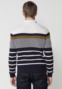 Jersey de punto con cuello, con franjas horizontales en blanco, azul marino y mostaza; tejido texturizado con puños y dobladillo acanalados.
