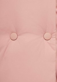 Růžová polstrovaná tkanina s prošívaným designem a dvěma kulatými knoflíky. Textura vypadá hladce, s jemným matným povrchem.