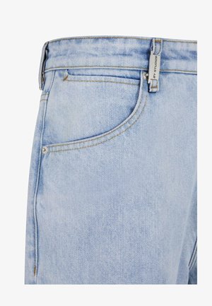 Jean en denim bleu clair avec une finition texturée, comprenant une poche avant, des passants de ceinture et des coutures contrastantes. Marquage subtil visible.