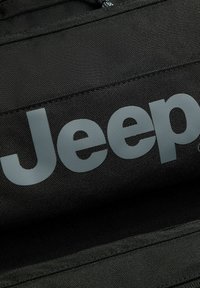 Bolsa de tela negra con un gran logo en gris claro de "Jeep". Presenta costuras resistentes y una superficie texturizada.