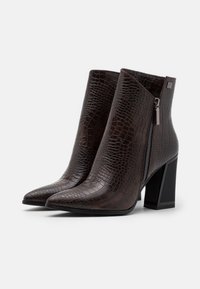 Botas de tobillo marrones con textura de cocodrilo, punta afilada, cremallera lateral y un tacón grueso negro. Acabado en cuero suave.