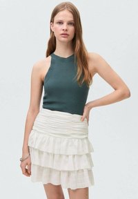 Geribbeld teal haltertop gecombineerd met een witte, gelaagde rokken met ruches. De outfit heeft een aansluitend ontwerp met een textuurstof in een lichte stijl.