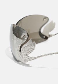 Sunglasses with a gray lens, metallic frame, and a swan accent adorned with clear crystals on the side for decoration and detail.