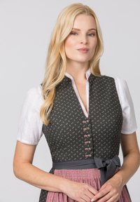 Traditionelles Dirndl mit einem dunkelblumigen Oberteil, weißer Bluse und pinkem Faltenrock. Mit grauem Taillenbund und dekorativen Knöpfen.