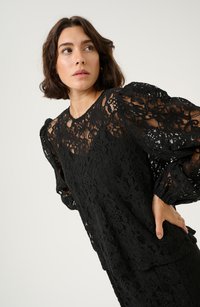 Black lace top featuring intricate floral patterns, puffed long sleeves, and a relaxed fit, showcasing a layered texture.