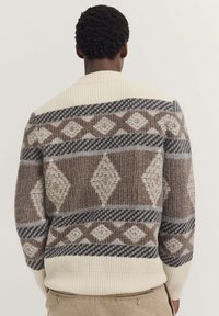 Maglione a maglia color crema, marrone e grigio; presenta un motivo geometrico a diamante e finiture a coste; peso medio, maniche lunghe.