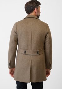 Brauner Wollmantel mit tailliertem Schnitt, ausgestattet mit Reverskragen, Rückenbelüftung und doppeltem Knopfdetail an der Taille.