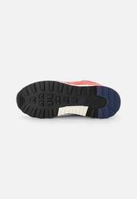 Sole of red sneaker with black, white, and blue tread, showing deep lugs and "Polo" branding on the black section of the outsole.