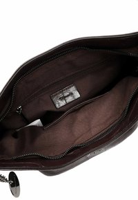 Brown leather handbag interior with a smooth texture, featuring a zip pocket, fabric lining, and a brand tag. Double zipper closure.