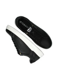 Zapatillas de cuero negras con suelas blancas, que presentan un acabado texturizado, ojales dorados y detalles perforados en los laterales.