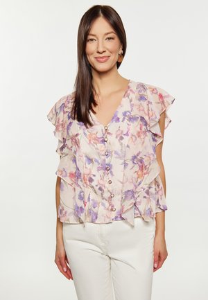 Florale blouse met gerimpelde mouwen, met een lichte crème basis en paars-roze bloemen. Knopen aan de voorkant en zachte, gewatteerde stof.