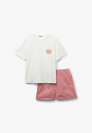 Chemise blanche à manches courtes avec un petit motif de pomme rose, associée à un short à carreaux vichy rouge et blanc.