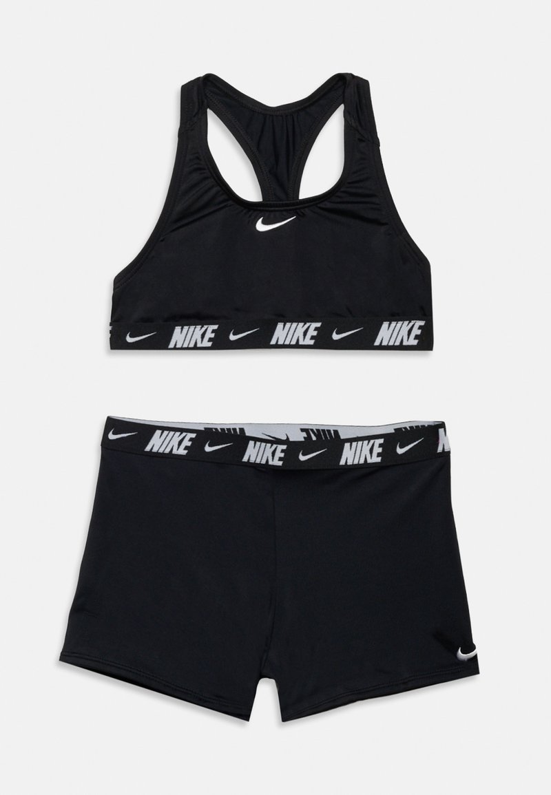 Μαύρο αθλητικό σετ Nike με αθλητικό σουτιέν racerback και σορτς με ελαστική μέση, και τα δύο με λευκά λογότυπα Nike και σχέδια swoosh.