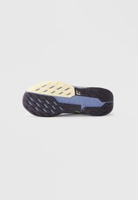 Suola della scarpa in gomma nera testurizzata con accenti gialli e blu, un motivo zigzag e branding in rilievo per aderenza e stabilità.