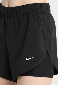 Musta urheilushortsit, joissa on joustava vyötärönauha, kerroksellinen design ja valkoinen Nike-logo alapuolella vasemmassa saumassa. Pehmeä, kevyt materiaali.
