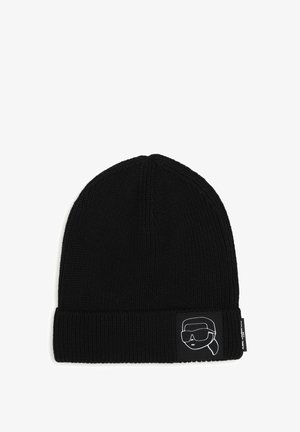 Bonnet noir en tricot avec un revers présentant un patch monochrome d’un visage stylisé portant des lunettes de soleil et un foulard.