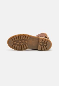 Braune Schuhsohle aus Gummi mit strukturiertem Muster für besseren Halt. Kreisförmiges Logo und Größenstempel sichtbar. Sauberes, minimalistisches Design.