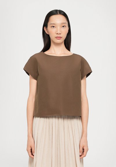 Brown cropped top with rounded neckline and short sleeves, made of smooth fabric. Paired with a pleated light-colored skirt.