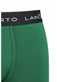 Zielone męskie bokserki z czarnym elastycznym paskiem w talii, na którym znajduje się biała marka. Materiał wydaje się gładki i dopasowany.