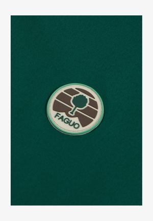 Sfondo in tessuto verde con un logo circolare. Il logo presenta il profilo di un albero e il testo "FAGUO," con una combinazione di colori marrone e bianco.
