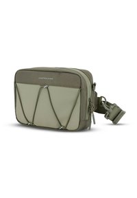 Borsa verde realizzata in tessuto testurizzato con un pannello inferiore liscio, dotata di un design con cordoncino elastico sul davanti e di una tracolla removibile.