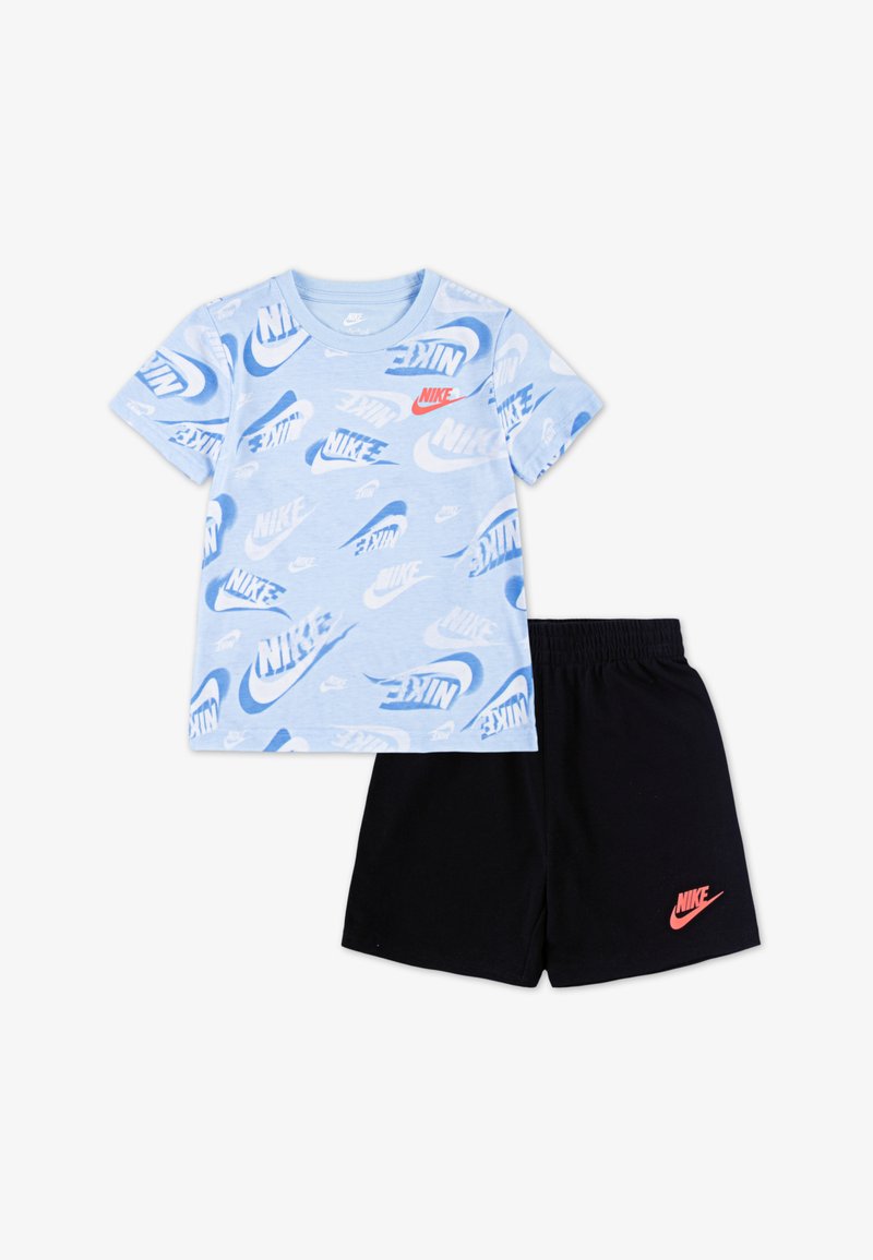 Világoskék póló, amelyen különböző árnyalatú Nike logók ismétlődnek, fekete rövidnadrággal párosítva, amelynek szélén piros Nike logo található.