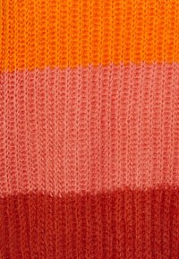 Close-up van ribgebreide stof met horizontale strepen in oranje, roze en roodbruin.