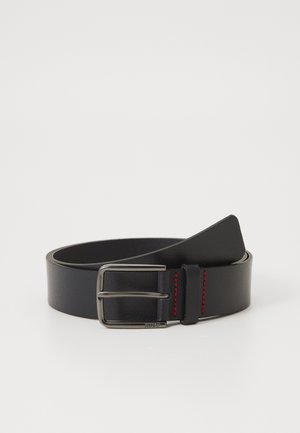 Ceinture en cuir noir avec une boucle en métal argenté. Présente des coutures rouges sur la boucle. Texture lisse et forme rectangulaire.